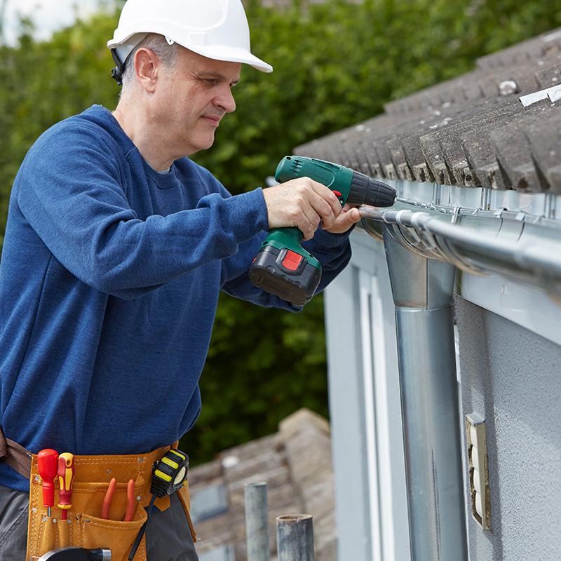 A man installing new gutter pipes for a residential house in Charlotte, NC